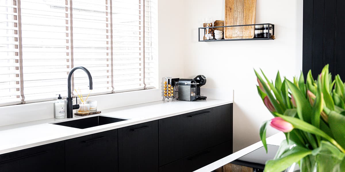 Zwarte keuken met wit werkblad en Quooker kraan